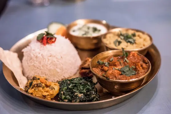 Nepalese dal bhat thali with rice, curry, dal, greens and papad