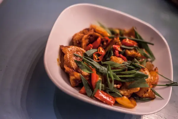 Chilli chicken bowl finished with spring onion and peppers