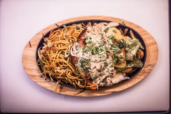 Sizzler platter with noodles, vegetables and creamy sauce