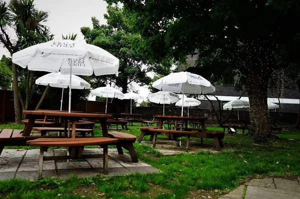 Beer garden with wooden picnic benches and white parasols